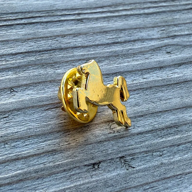 Goldener Ansteck-Pin in Form eines goldenen Rosses, der auf Holz liegt