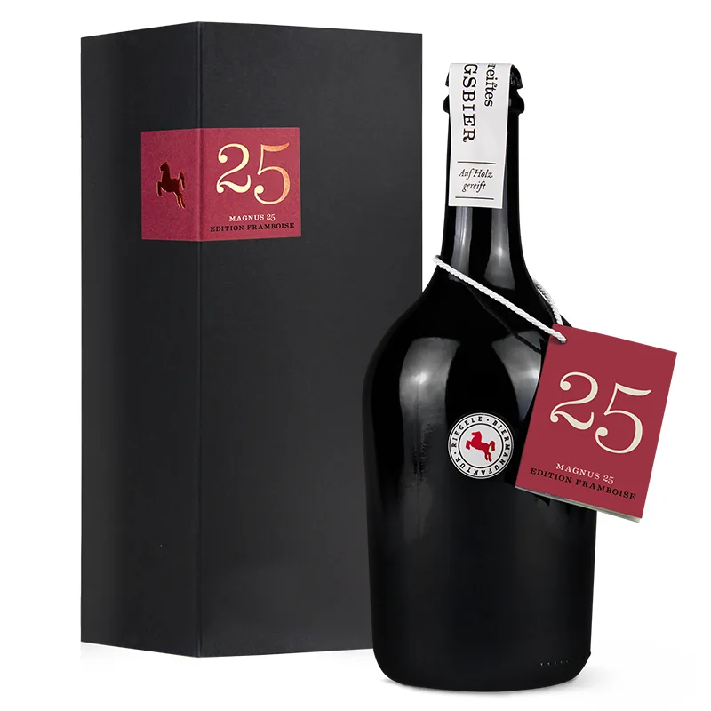Elegante Flasche mit rotem Umhänger, auf dem die Zahl 25 zu sehen ist. Edle schwarze Schachtel daneben mit rotem Aufkleber.